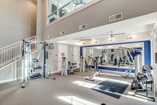 A spacious gym with a variety of equipment and a staircase.
