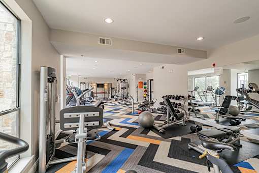 A gym with a variety of equipment including treadmills, weights, and exercise machines.
