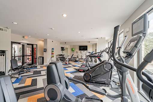 A gym with a variety of equipment including treadmills and stationary bikes.