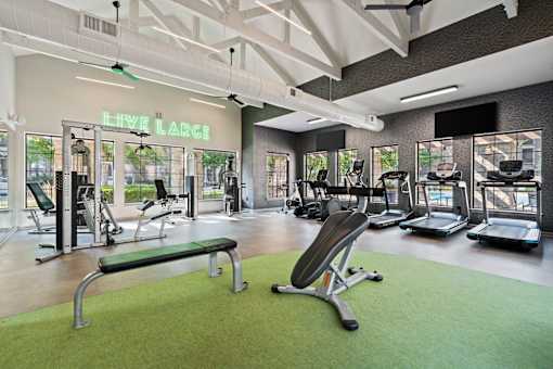 A gym with a green floor and a neon sign that says "LIVE LARGE".