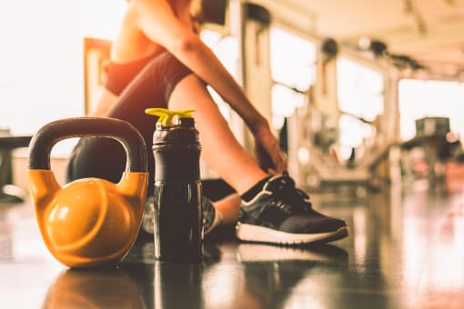 a woman sitting in a gym with a kettlebell and water bottle in front of her