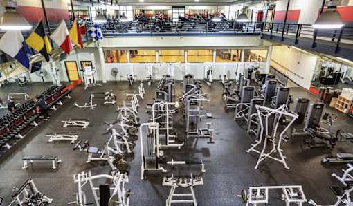 A gym with a variety of equipment and flags hanging from the ceiling.