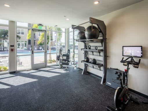 a workout room with a bike and a tv
