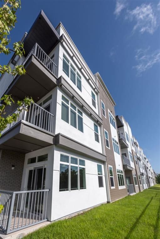 a white and brown apartment building with a lawn