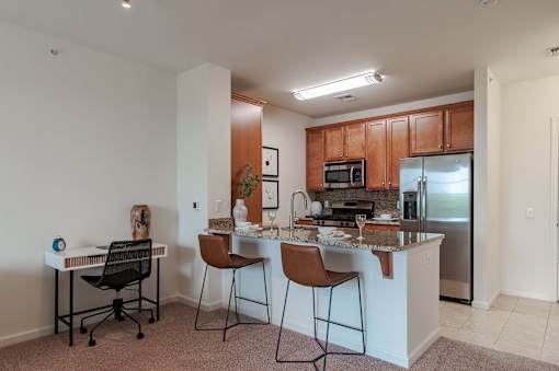 A kitchen with a white countertop and brown chairs.