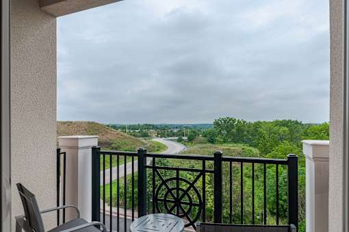 A balcony with a black railing and a view of a winding road.