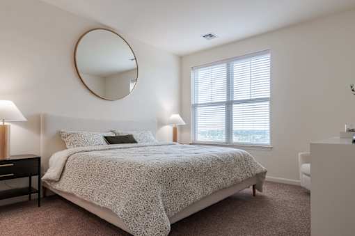 A bedroom with a round mirror on the wall.