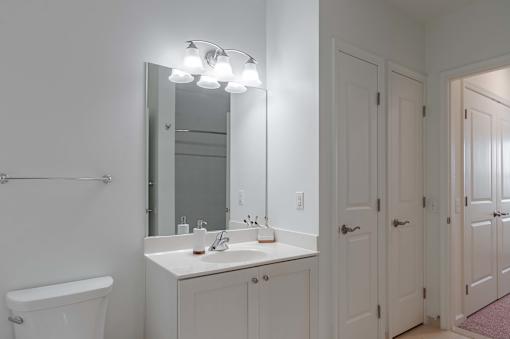 A white bathroom with a sink, mirror, and toilet.