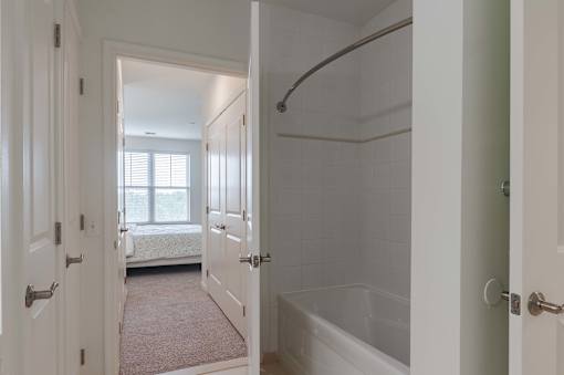 A white bathroom with a tub and a window.