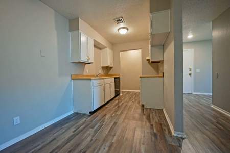 A kitchen with white cabinets and a wooden floor.