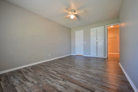 A room with a ceiling fan and wood flooring.