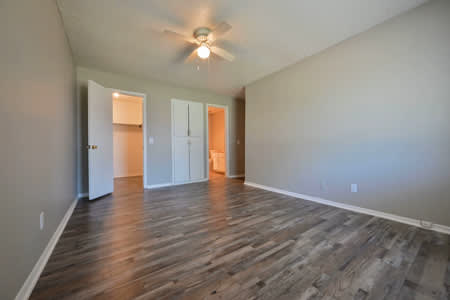 A room with a ceiling fan and wooden flooring.