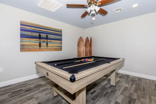 a game room with a pool table and a surfboard on the wall