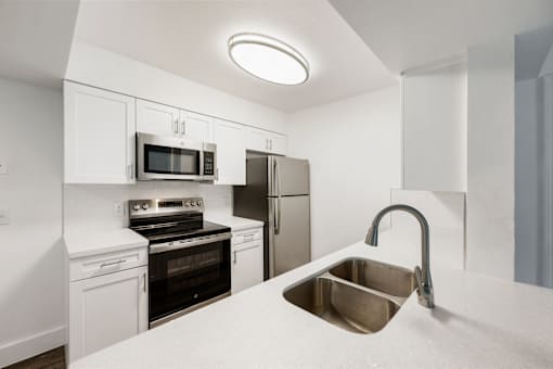 a kitchen with white cabinets and stainless steel appliances