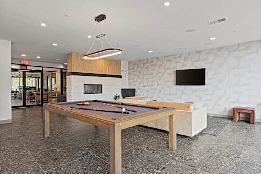 A pool table is in the middle of a room with a stone wall.