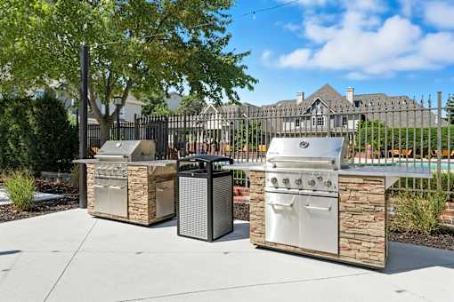 Three outdoor grills are placed on a patio.