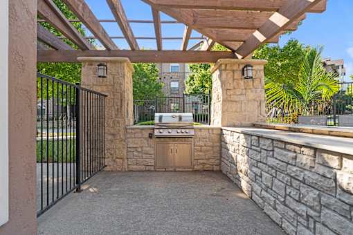 A patio with a black gate and a stone wall.
