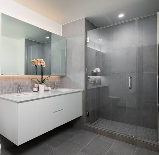 A modern bathroom with a white sink vanity and a walk-in shower.