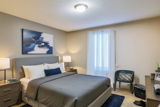 A bedroom with a large bed, a chair, and a painting on the wall.
