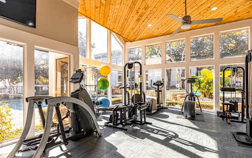 A gym with a variety of equipment including treadmills, weights, and a television.