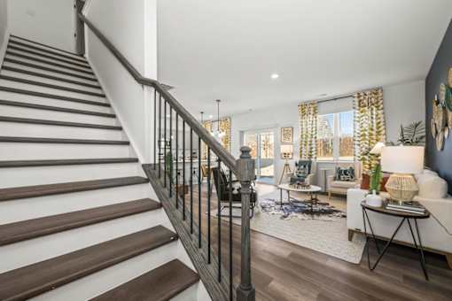 A staircase with a metal railing leads to a living room with a couch and a coffee table.
