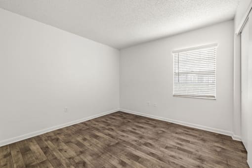 the spacious living room with wood flooring and a window