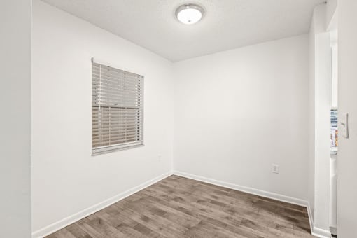 an empty room with a window and wood flooring