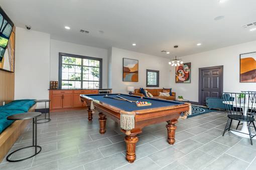 A pool table is in the middle of a room with a blue cushion on it.