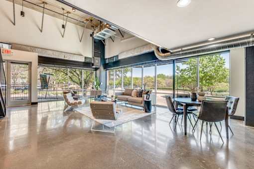 A spacious room with a dining table and chairs, and a sofa with a cushion.