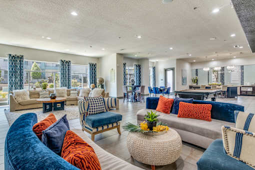 A living room with a blue velvet sofa and a woven coffee table.
