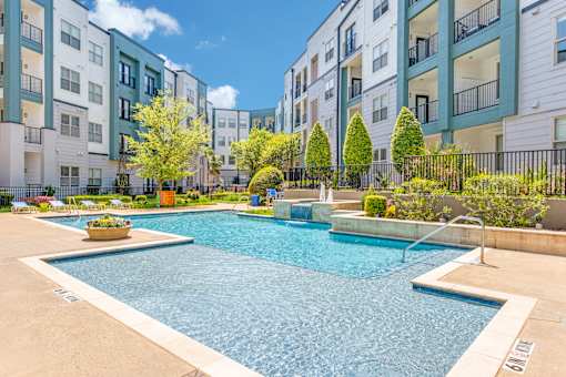 A swimming pool in a residential area surrounded by trees and buildings.