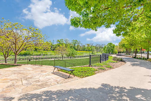 A park with a bench and a fence.