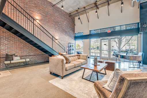 A living room with a couch, a coffee table, and a staircase.
