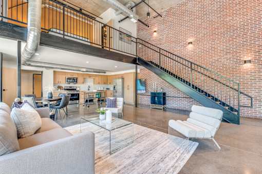 A living room with a grey couch and a glass coffee table.