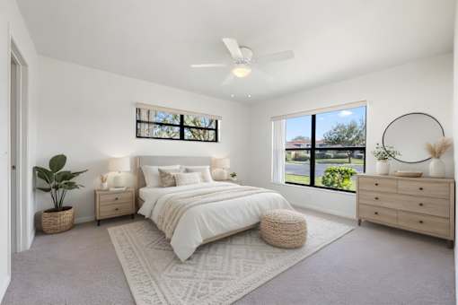 A bedroom with a large bed, a ceiling fan, and a window with a view of the outdoors.