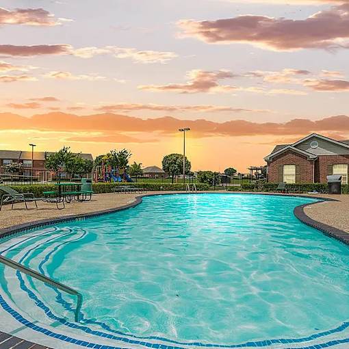 A large swimming pool with a sunset in the background.