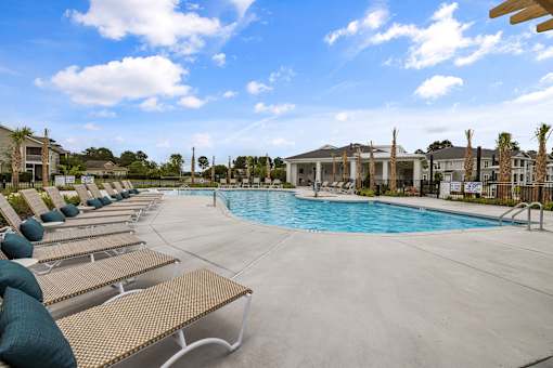 A pool area with sun loungers and a clear blue sky.