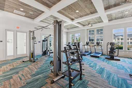 A gym with a variety of equipment including treadmills, weights, and exercise bikes.