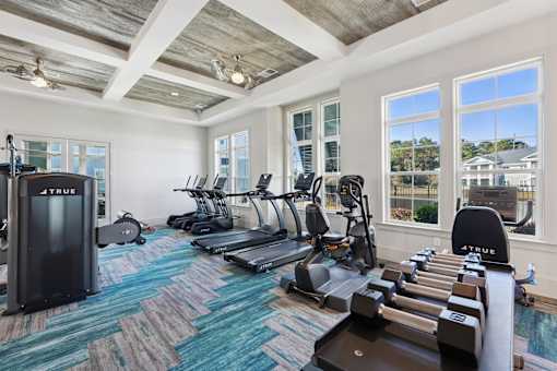 A gym with a variety of equipment including treadmills, elliptical machines, and dumbbells.