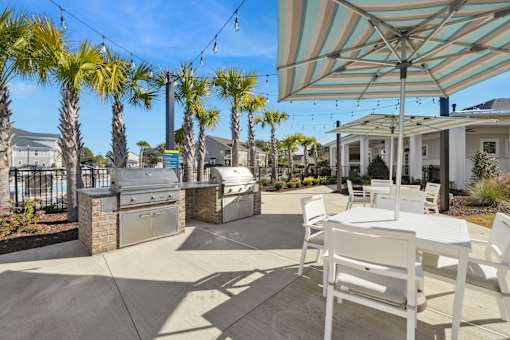 A patio with a table and chairs under a striped umbrella.