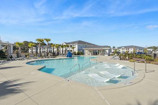 A large outdoor swimming pool with a slide and a building in the background.