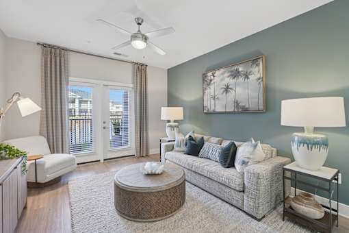 A living room with a grey couch, a round coffee table, and a painting on the wall.
