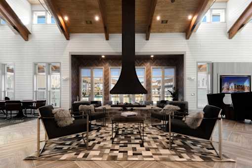 A modern living room with a black and white checkered rug and a large black fireplace.