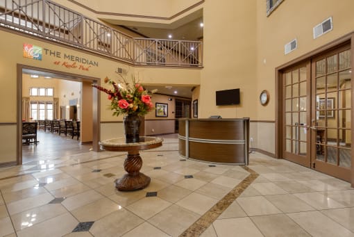 the lobby of a hotel with a reception desk and a vase of flowers