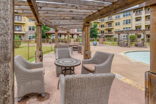 a patio with wicker chairs and a table next to a pool