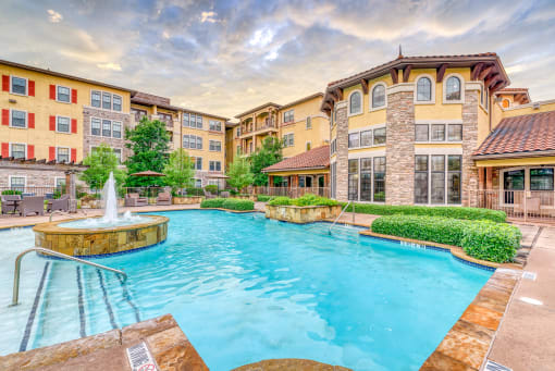 a swimming pool with a fountain in front of an apartment building