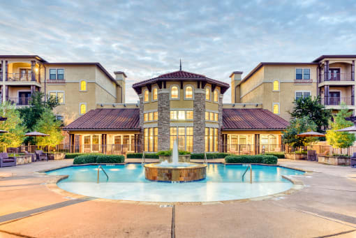 a swimming pool with a fountain in front of an apartment building