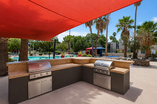 A red canopy is over a barbecue grill.