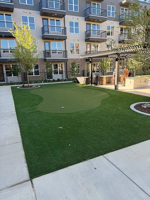 A small putting green in front of apartment buildings.