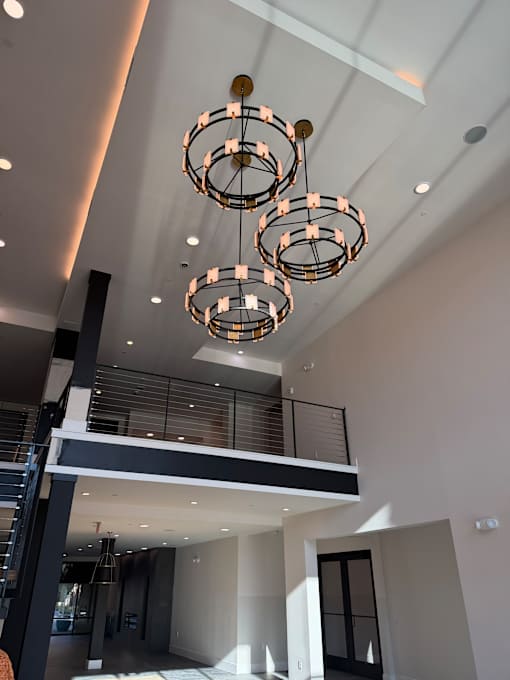 A modern chandelier hangs from the ceiling in a spacious room.